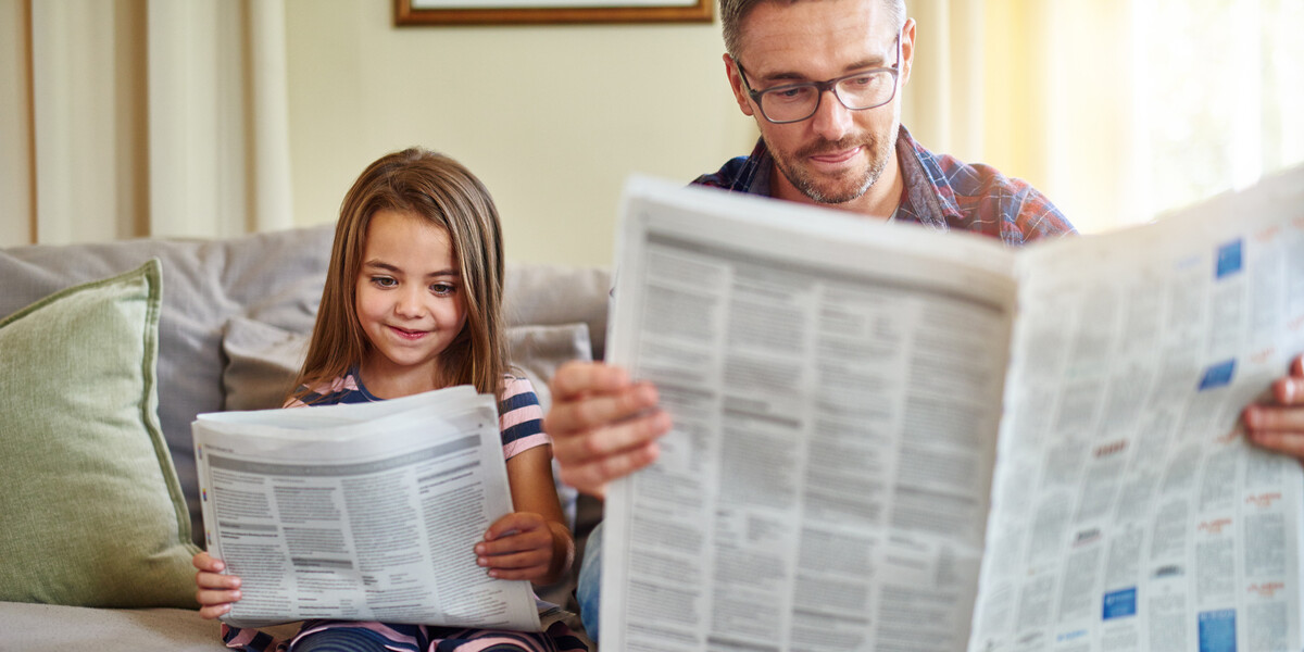 Vater und Tochter lesen Wochenzeitung