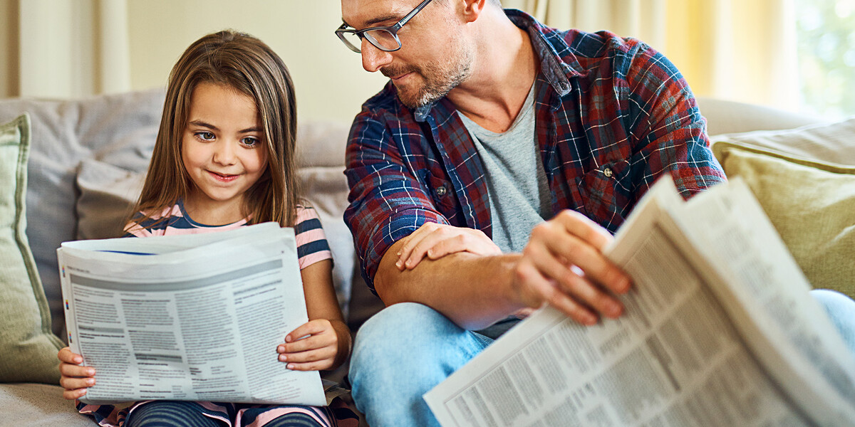 Vater und Tochter lesen Wochenzeitung