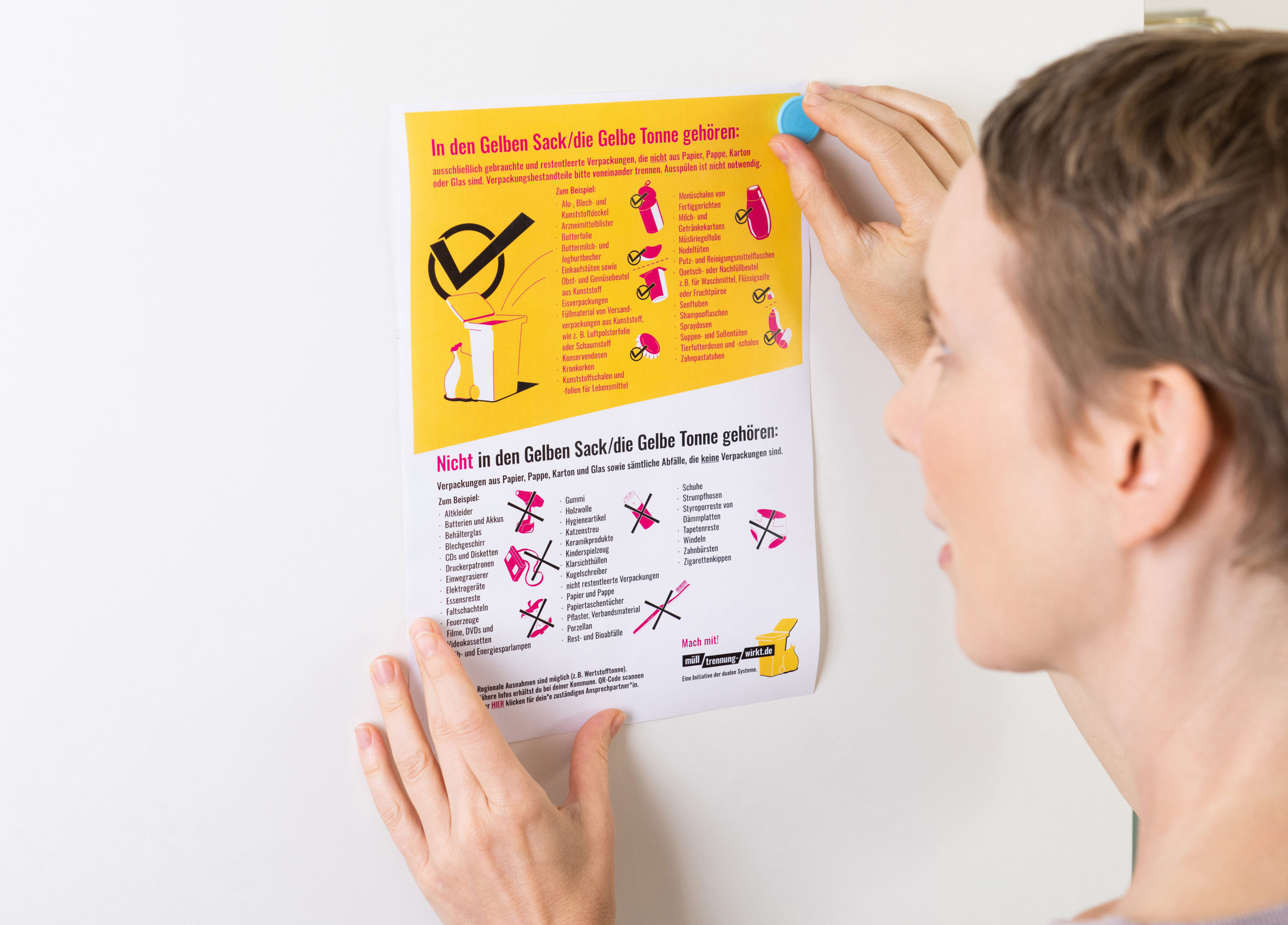 Frau pinnt die Trenntabelle "Was gehört in den gelben Sack" an ihren Kühlschrank
