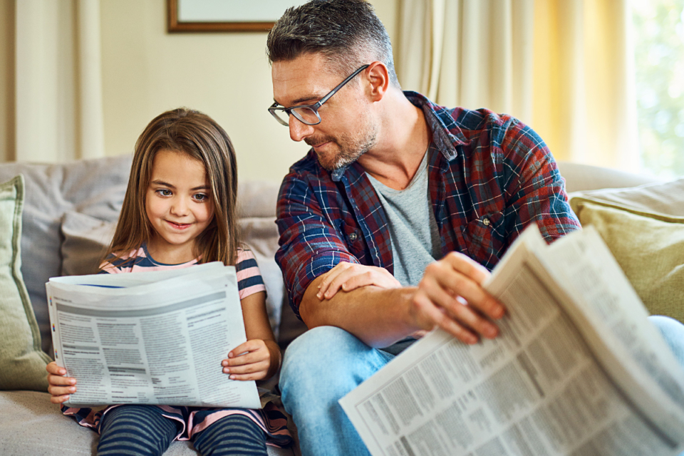 Vater und Tochter lesen kostenlose Wochenzeitung